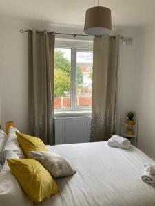 Gresham House - London Excel في لندن: غرفة نوم بسرير ومخدات صفراء ونافذة
