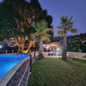 a resort with palm trees and a swimming pool at night at Arcaloro Resort Rooms Ghiro in SantʼAngelo di Brolo