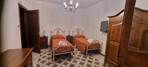 a bedroom with two beds and a chandelier at Arcaloro Resort Rooms Ghiro in SantʼAngelo di Brolo