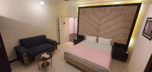 a small bedroom with a bed and a chair at Shelton House in Karachi