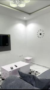 a white room with a table and a clock on the wall at 1bedroom serviced apartment in Benin City in Benin City