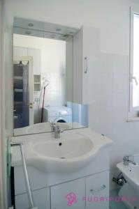 uma casa de banho branca com um lavatório e um espelho em Borgo San Giuseppe 16 em Parma