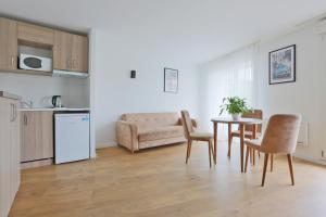 a kitchen and a living room with a table and chairs at KOSY Appart'Hôtels - La Maison Des Chercheurs in Vandoeuvre-lès-Nancy