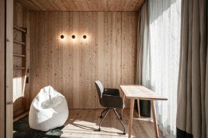 Zimmer mit einem Stuhl, einem Schreibtisch und einem Fenster in der Unterkunft OLM Nature Escape - Eco Aparthotel in Sand in Taufers