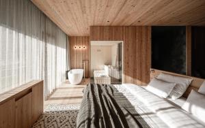 a bedroom with a bed and a tub in a room at OLM Nature Escape - Eco Aparthotel in Campo Tures