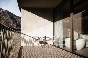 balcón con mesa, sillas y bañera en OLM Nature Escape - Eco Aparthotel, en Campo Tures