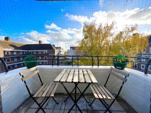 a wooden table and two chairs on a balcony at 2 Bed- Belsize Park in London