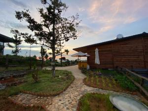 a garden with a house and a tree and a building at Lam Nguyên Farm Stay in Bao Loc