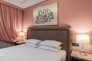 ミラノにあるDoria Grand Hotelのベッドルーム1室(ランプ2つ、壁に絵付)