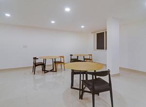 2 Tische und Stühle in einem Zimmer mit einer weißen Wand in der Unterkunft Super Townhouse 862 Che Sigma in Hyderabad
