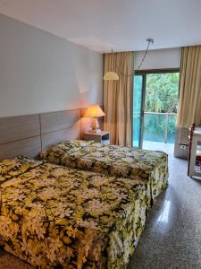 a hotel room with two beds and a window at Royalty Copacabana Hotel in Rio de Janeiro