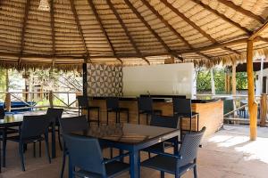 eine Terrasse mit Tischen und Stühlen unter einem Strohdach in der Unterkunft Bangalô da Barra, chalé 04 - BG in Barra Grande