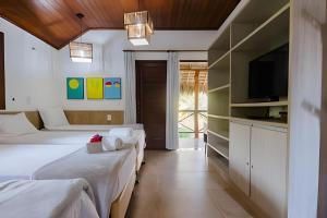 ein Hotelzimmer mit zwei Betten und einem Fernseher in der Unterkunft Bangalô da Barra, chalé 04 - BG in Barra Grande