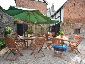 un patio con mesas y sillas y una sombrilla verde en 9 Bed in Welshpool 40870, en Llanfyllin