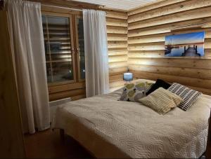 1 dormitorio con 1 cama con pared de madera en Holiday home with lake view and next to National Park, en Kolinkylä