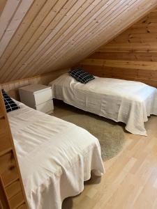two beds in a room with wooden walls at Holiday home with lake view and next to National Park in Kolinkylä