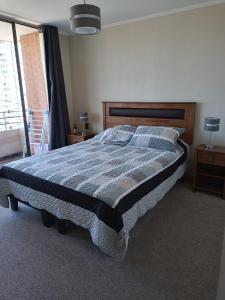 1 dormitorio con 1 cama con manta azul y gris en Delpino Propiedades 4 Norte, Viña del Mar, en Viña del Mar