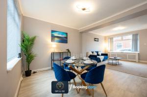a living room with a table and blue chairs at Luxurious & Spacious 2 Bedroom Home By Opuluxe Properties Short Lets & Serviced Accommodation Near Manchester City Center in Manchester