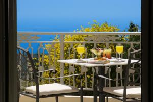 a table and chairs on a balcony with wine glasses at Belle View Hotel - Sea View & Sunset in Mánganos