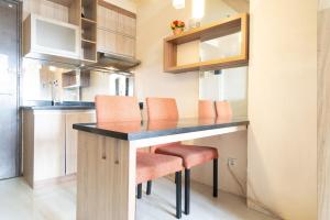 a kitchen with a table and orange chairs at THE SUITES METRO BY GOODVIBES APARTMENT in Bandung