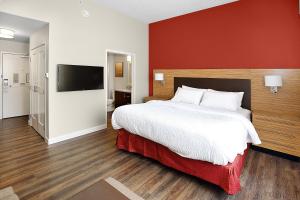1 dormitorio con 1 cama grande y pared roja en TownePlace Suites by Marriott Grove City Mercer/Outlets, en Grove City