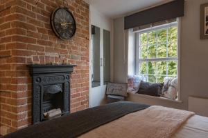 a bedroom with a fireplace and a clock on a brick wall at Cow and Cockle - quirky cottage in the centre of Deal in Deal