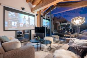 Una gran pantalla en una habitación con sofás y una mesa. en Chalet Seven Summits - Pool - Sauna - Jacuzzi en Chamonix-Mont-Blanc