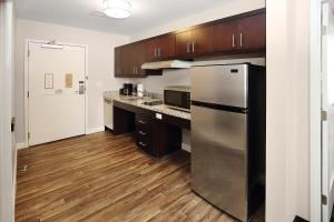 a kitchen with a stainless steel refrigerator and wooden cabinets at TownePlace Suites by Marriott Grove City Mercer/Outlets in Grove City