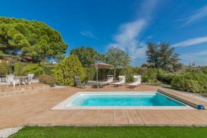 einen Pool in einem Garten mit Stühlen und einem Sonnenschirm in der Unterkunft Villa Editha in Calonge