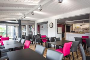 restauracja ze stołami, krzesłami i różowymi krzesłami w obiekcie Logis hôtel restaurant la Haute Forêt w mieście Vertou