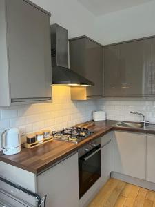 a kitchen with white cabinets and a stove top oven at Stylish One Bedroom Apartment in the heart of Angel in London