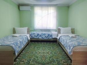 a room with two beds and a rug at Uyut house Osh in Osh