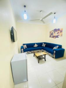 een woonkamer met een blauwe bank en een tafel bij Huwari Apartments in Aqaba