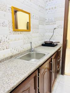 een badkamer met een wastafel en een spiegel bij Huwari Apartments in Aqaba