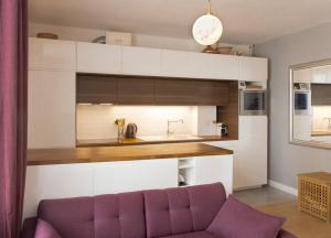 a living room with a purple couch in front of a kitchen at Joli Duplex Confort T2 Paris Porte De Versailles in Vanves