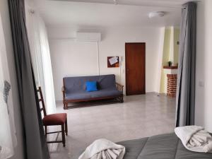 ein Wohnzimmer mit einem blauen Sofa und einem Stuhl in der Unterkunft Apartamentos Campos 1 in Porto Covo