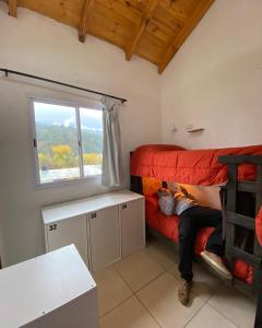 a person sitting on a bunk bed in a room at Hostel Otto Tipp in El Bolsón