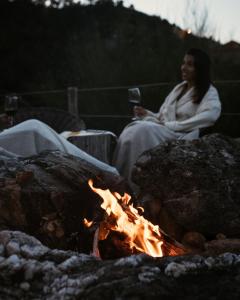 a woman sitting next to a camp fire at Cerquido by NHôme in Cerquido