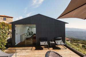 una casa negra en una terraza de madera con sillas en Cerquido by NHôme en Cerquido