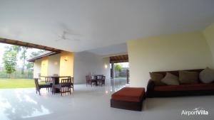 een woonkamer met een bank en een tafel en stoelen bij Airport Villa in Katunayaka