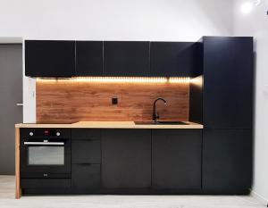 a kitchen with black cabinets and a sink at Apartment Quiet Street 11/7E in Oświęcim