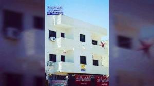 a white building with black windows and a red star at Huwari Apartments in Aqaba