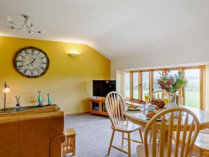 a dining room with a table and a clock on the wall at 2 Bed in Axminster 45099 in Axminster