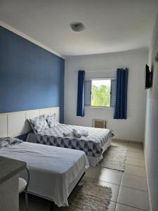 una camera con due letti con pareti blu e una finestra di Hotel e Marina nova pier 22 a Caraguatatuba