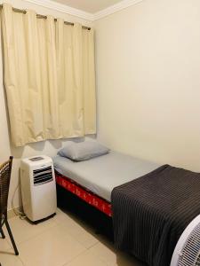 um pequeno quarto com uma cama e uma janela em Aluga-se Apartamento todo no Parque Caravelas em Ipatinga