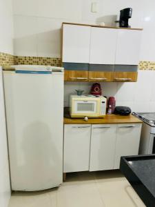 uma cozinha com um frigorífico branco e um micro-ondas em Aluga-se Apartamento todo no Parque Caravelas em Ipatinga