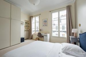 1 dormitorio con cama, escritorio y ventana en Veeve - Flowers in Saint-Martin en París