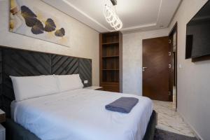 1 dormitorio con 1 cama blanca grande y cabecero marrón en Apart Hotel IMMOKA, en Tánger