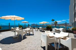 un restaurante con mesas blancas y sombrillas en la azotea en Kn Hotel Arenas del Mar Adults Only, en El Médano