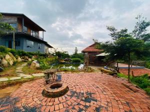 a brick patio with a fountain in front of a house at Lam Nguyên Farm Stay in Bao Loc